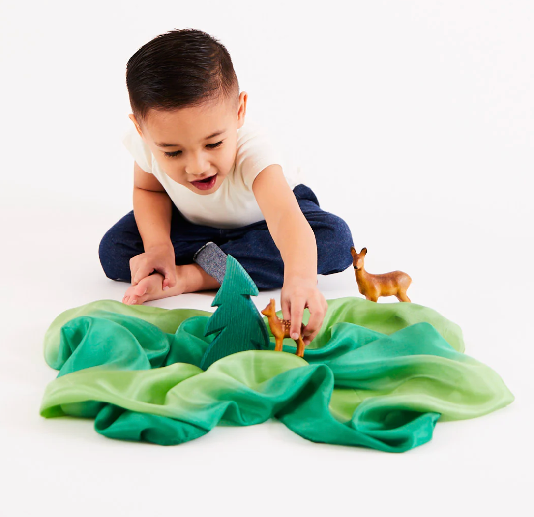 A child plays on a green, earth playsilk The Doodle Post